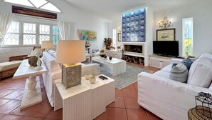 Ein Wohnzimmer mit einer Couch, einem Couchtisch, einem Fernseher und einem Kamin.