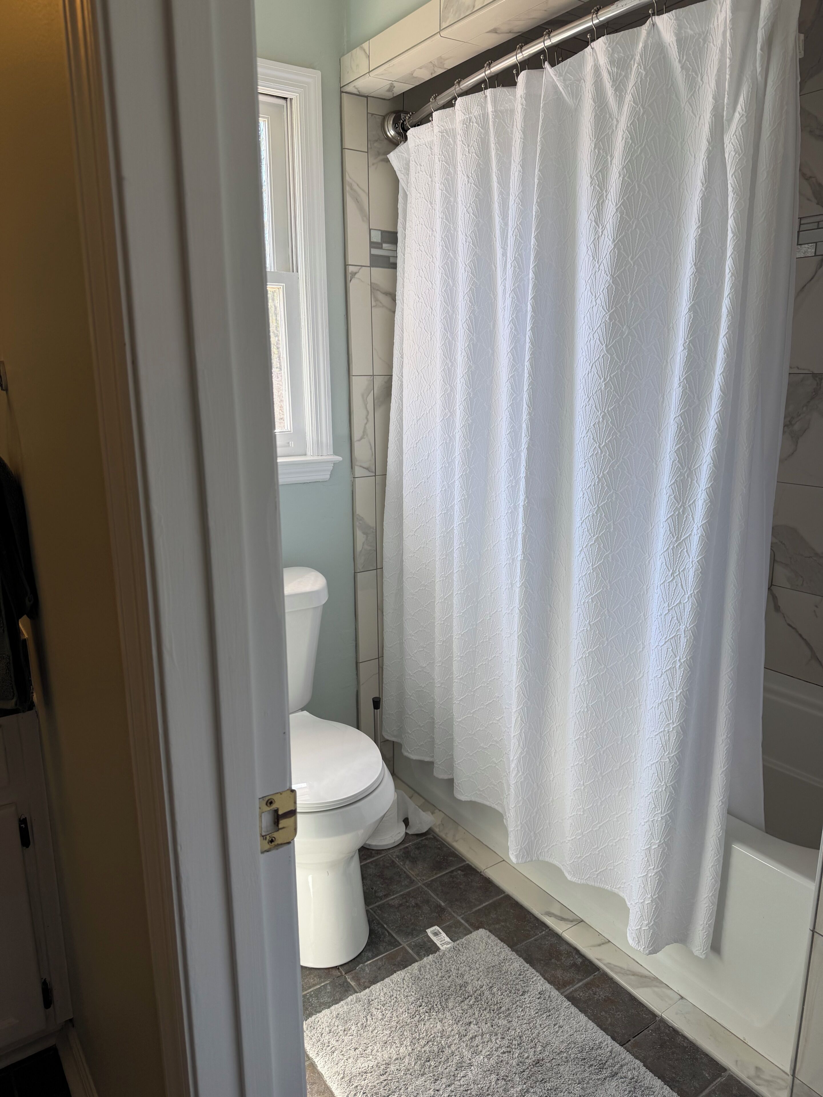 Un baño con inodoro, cortina de ducha y alfombra.
