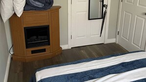 A bedroom with a bed, a wooden cabinet, and a white door with a mirror. - Oakhill Oasis Guest House (Oak Hill)