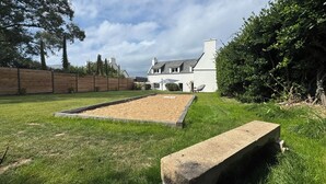 Ein Haus mit großem Garten, Holzzaun und Stehbank.