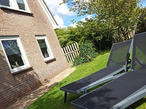 A brick building with two windows, a wooden fence, and a lawn. - Contemporary Family Haven in Noordwijk (Noordwijk)