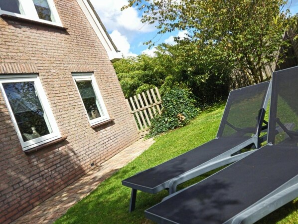 A brick building with two windows, a wooden fence, and a lawn. - Contemporary Family Haven in Noordwijk (Noordwijk)
