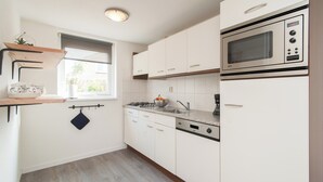 Egy modern konyha fehér szekrényekkel, beépített sütővel és egy ablakkal.