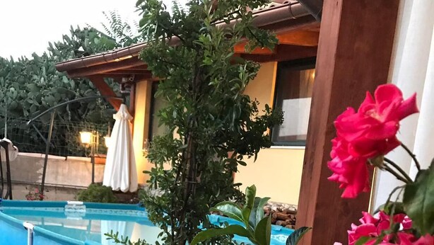 A pool area with a large planter filled with flowers and a small stool. - La casa di Gio'- Apartamento Rustico Legno (CALTANISSETTA)