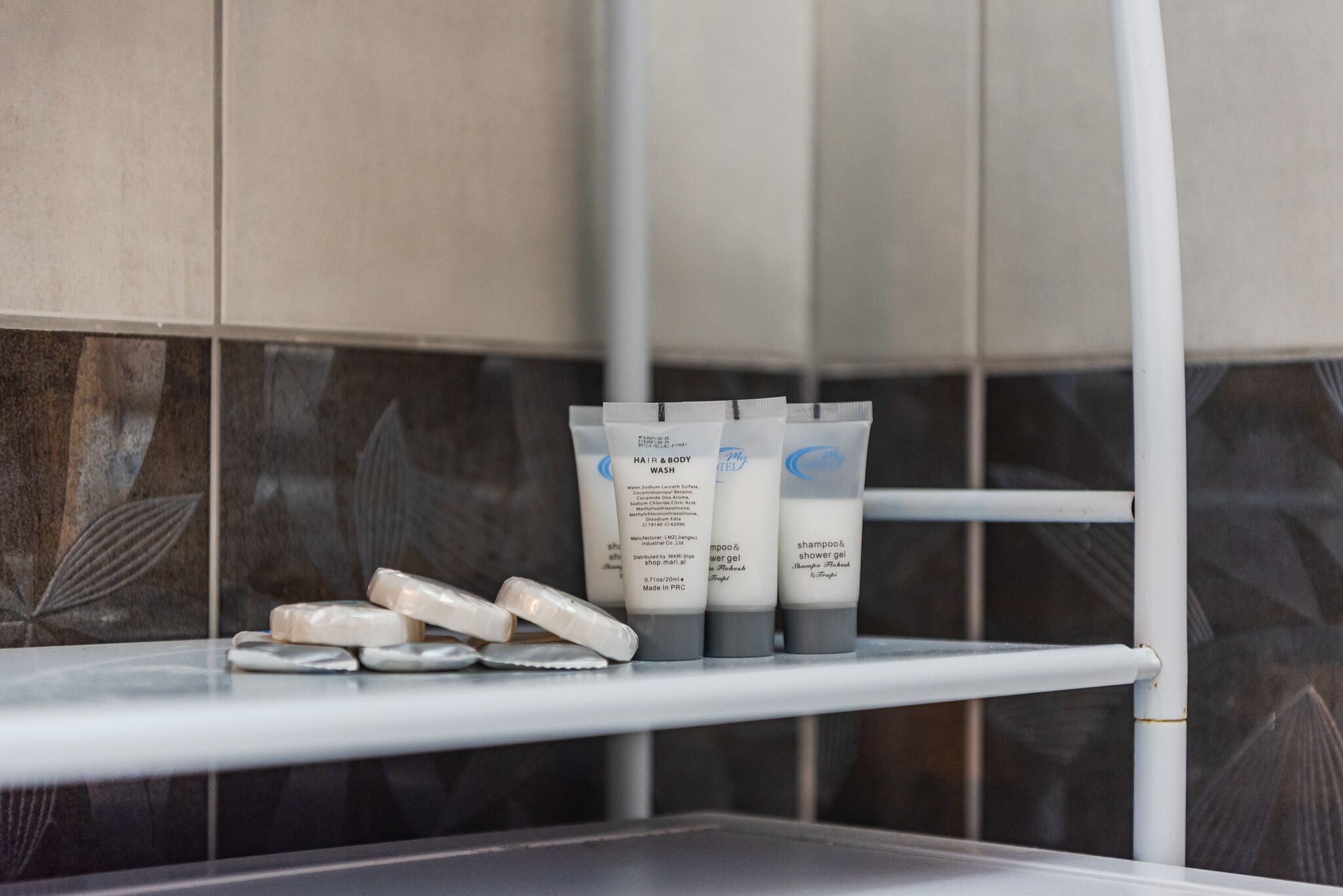 A bathroom shelf with toiletries including hair and body wash, shampoo, and shower gel.