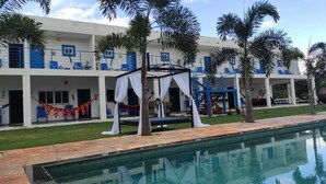 A hotel with a pool, outdoor seating, and palm trees. - pousada ibiza (Pirenopolis)