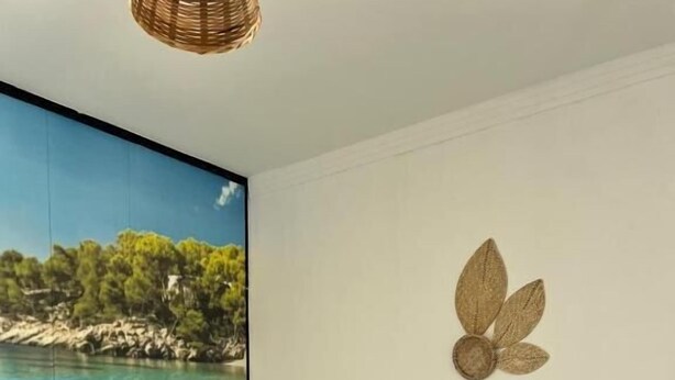 A hotel room with a large window offering a scenic view of a coastal landscape, a bed with white linens, and a decorative wall piece. - pousada ibiza (Pirenopolis)