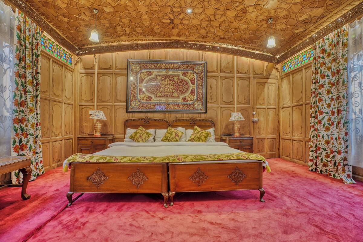 A traditional room with a wooden bed, a large ornate mirror, and a red carpet.