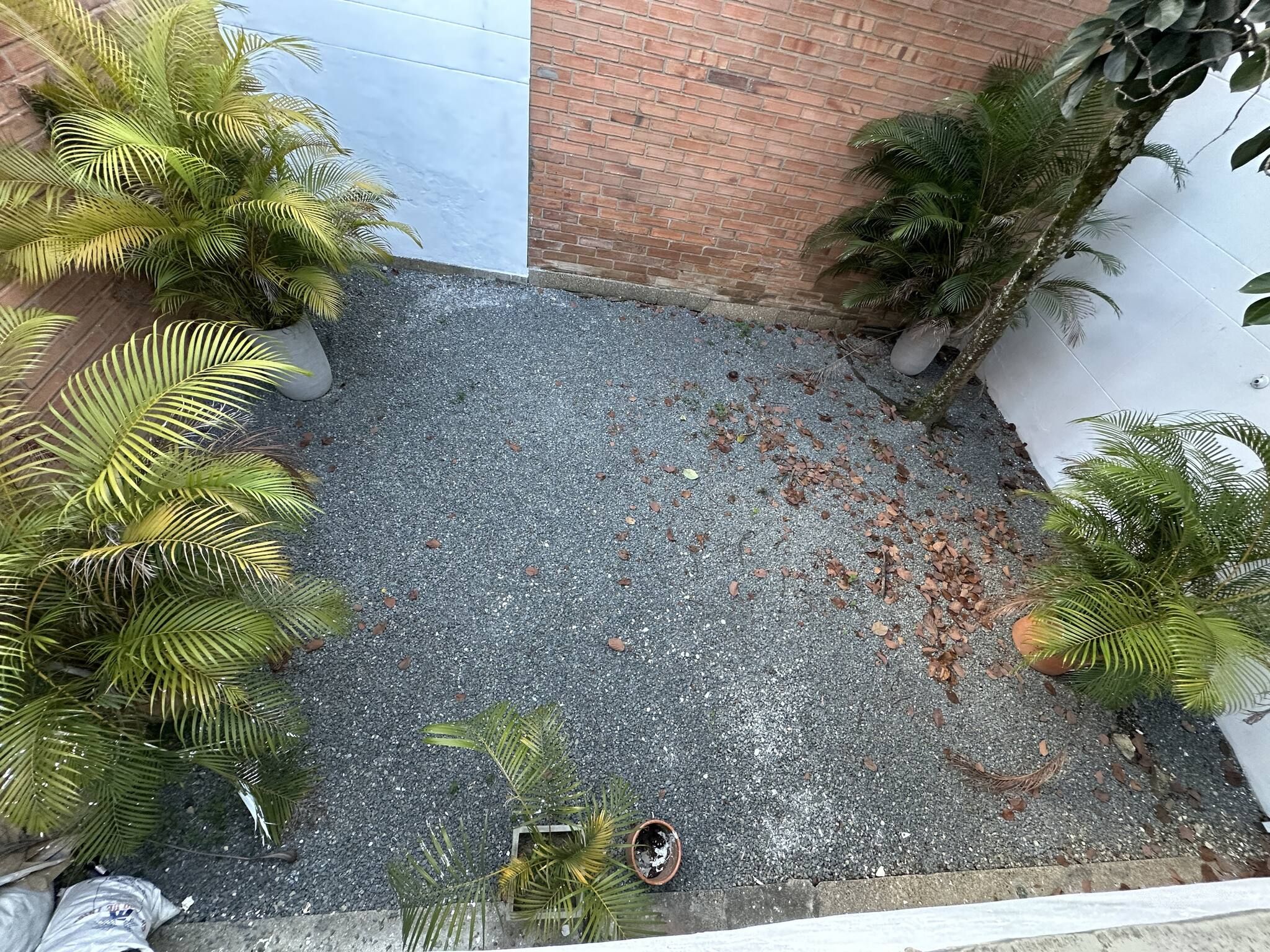 Ein Innenhof mit Kiespflaster, Blumentöpfen und einer Backsteinmauer.