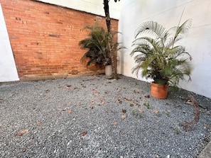 A courtyard with a gravel ground, a brick wall, and two potted plants. - Group Stay 21 Guests, Wifi 900 Mb (Medellín)