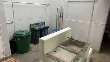 A small, enclosed bathroom with a sink, two trash bins, and a handwashing station.