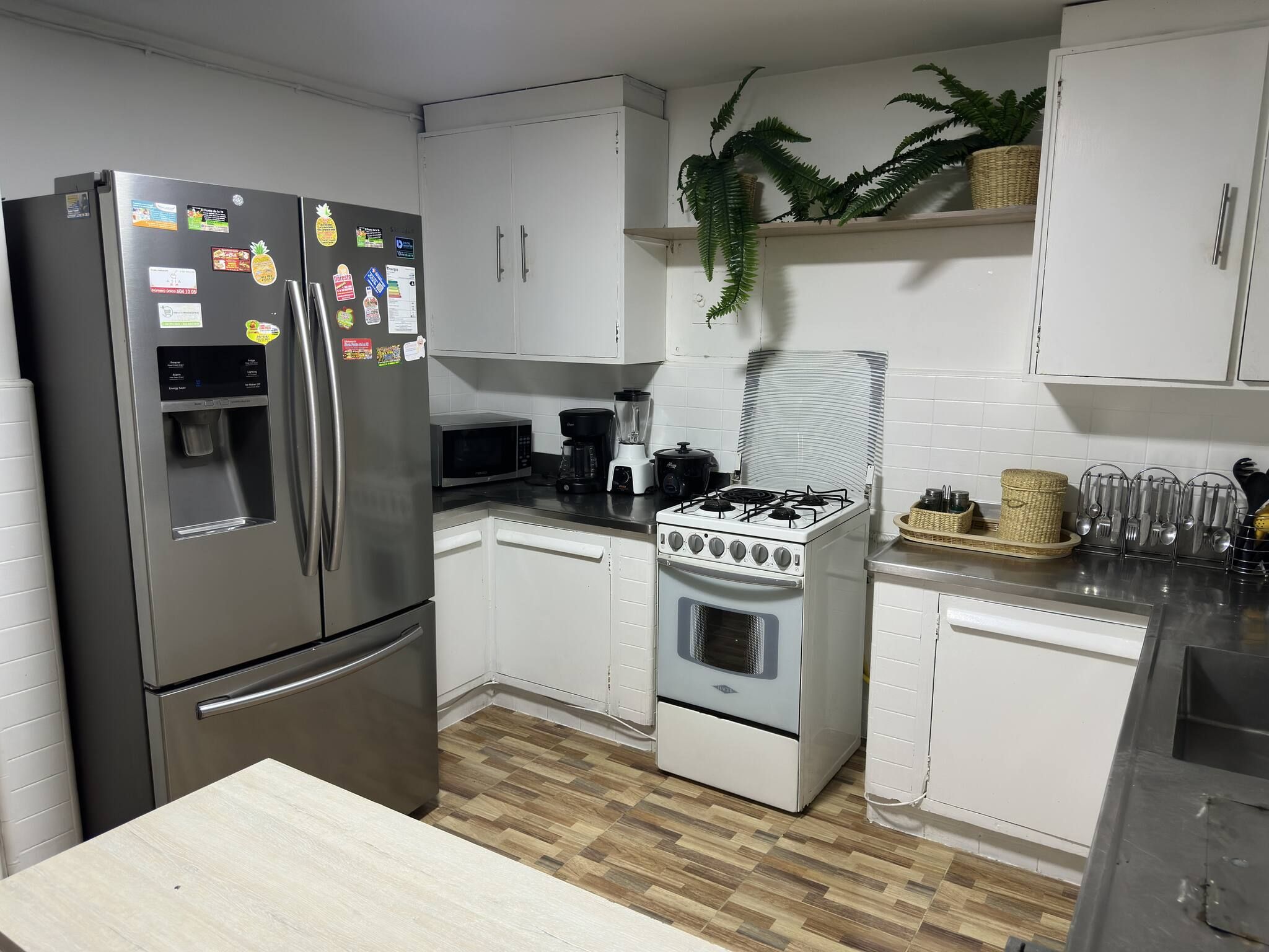 A modern kitchen with stainless steel appliances, white cabinets, and a wooden floor.