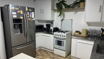 A modern kitchen with stainless steel appliances, white cabinets, and a wooden floor.