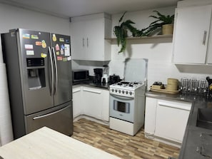A modern kitchen with stainless steel appliances, white cabinets, and a wooden floor. - Group Stay 21 Guests, Wifi 900 Mb (Medellín)