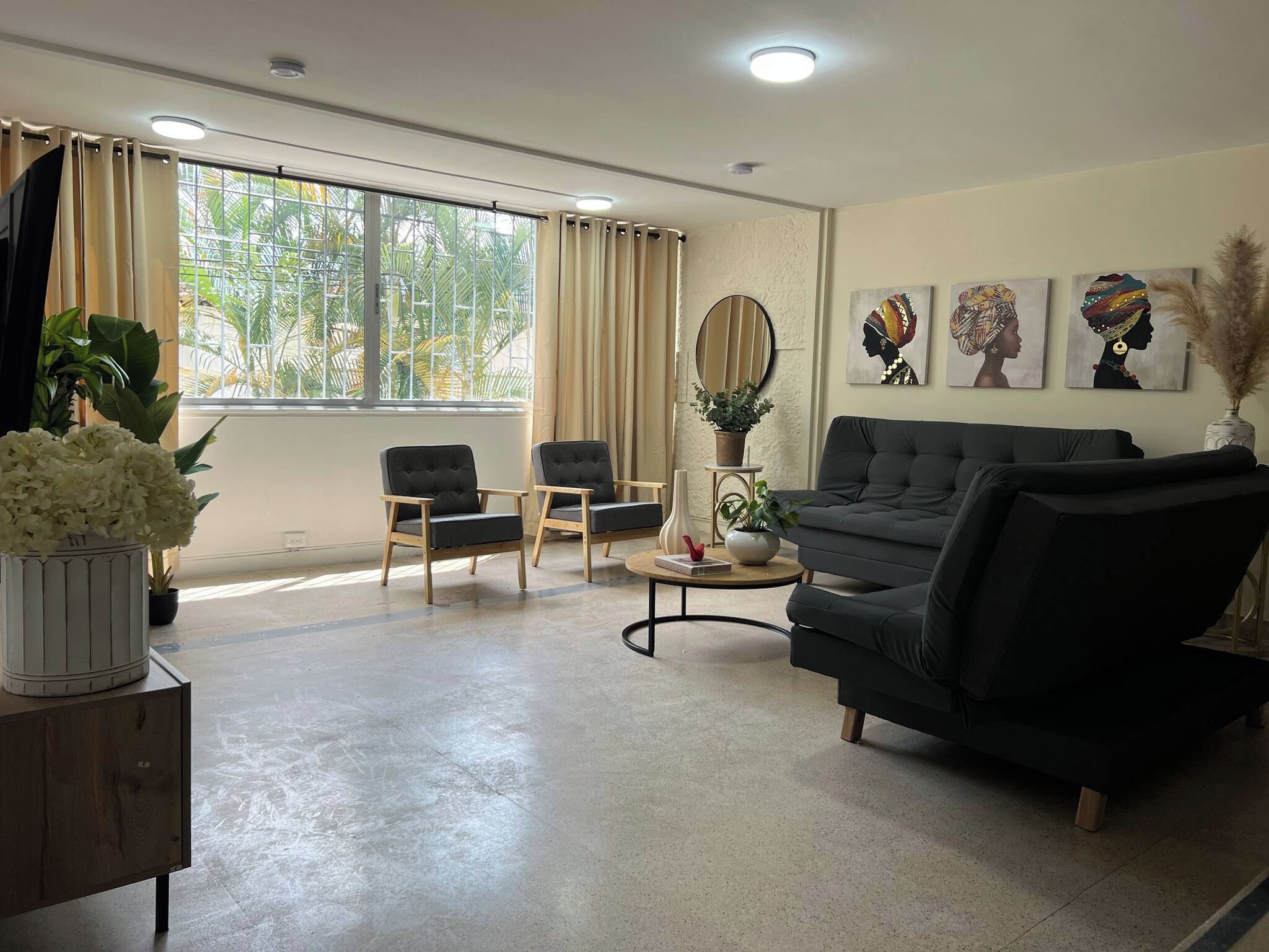 A living room with a sofa, two armchairs, a coffee table, and a potted plant.