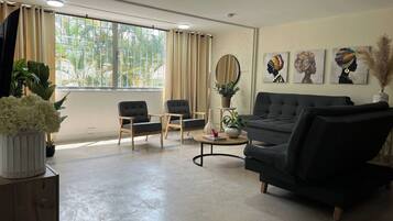 A living room with a sofa, two armchairs, a coffee table, and a potted plant.
