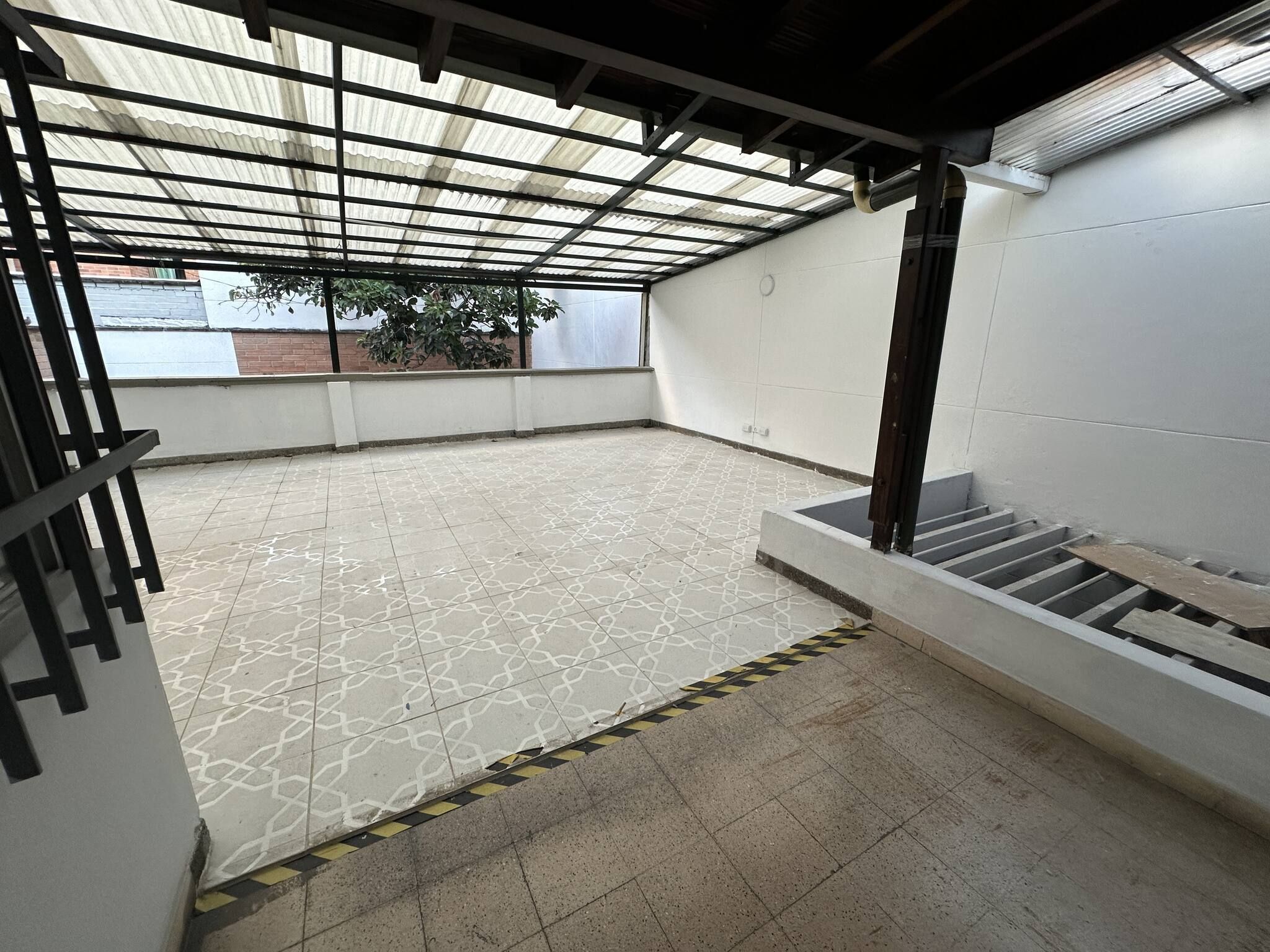 Ein leerer Raum mit einem gemusterten Boden, einer Metalltreppe und einer Stahlkonstruktion an der Decke.