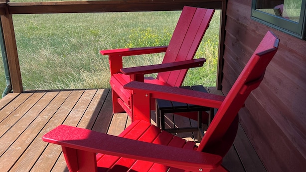 A red Adirondack chair on a wooden deck with a view of mountains. - Newly Renovated 3-bedroom home near Yellowstone National Park (Livingston)