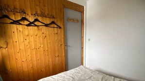 Un dormitorio con pared de paneles de madera, una cama con edredón blanco y una puerta con paneles de madera.