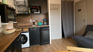 Una cocina compacta con lavavajillas, microondas y una lámpara colgante.