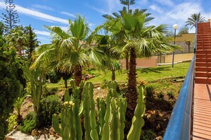 A garden with cacti and palm trees, a brick wall, and a lamp post. - 139 - Modern Coastal Apartment with Pool & Sea Views in La Cala de Mijas (La Cala de Mijas)