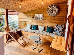 A wooden interior with a bench, a cushioned chair, a small table, and a hanging decoration.