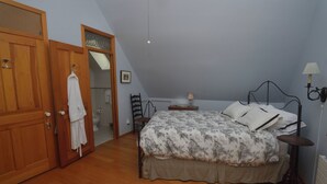 A bedroom with a bed, a wooden wardrobe, a chair, a bedside table, and a lamp. - Adorable 1-bedroom cottage with AC in Shelter Island (Shelter Island)