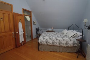 Ein Schlafzimmer mit einem Bett, einem Holzschrank, einem Stuhl, einem Nachttisch und einer Lampe.