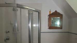 A bathroom with a glass-enclosed shower, a toilet, and a small window above the sink. - Adorable 1-bedroom cottage with AC in Shelter Island (Shelter Island)