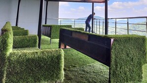 Un balcon offrant une vue sur un paysage montagneux, avec une personne debout sur une corniche.