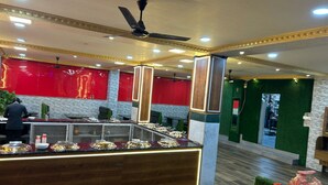 Un restaurant moderne avec un comptoir en bois, une décoration aux couleurs rouge et verte, et un ventilateur de plafond.