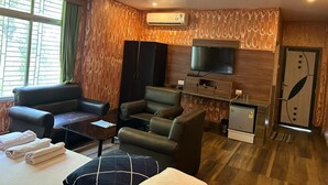 Un salon avec un canapé, des fauteuils, un téléviseur et un petit réfrigérateur.