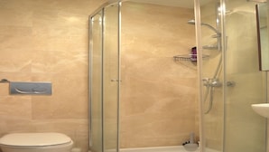 Un baño moderno con ducha acristalada, inodoro y lavabo.