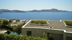 Una terraza en la azotea con vistas a un mar tranquilo y montañas lejanas.