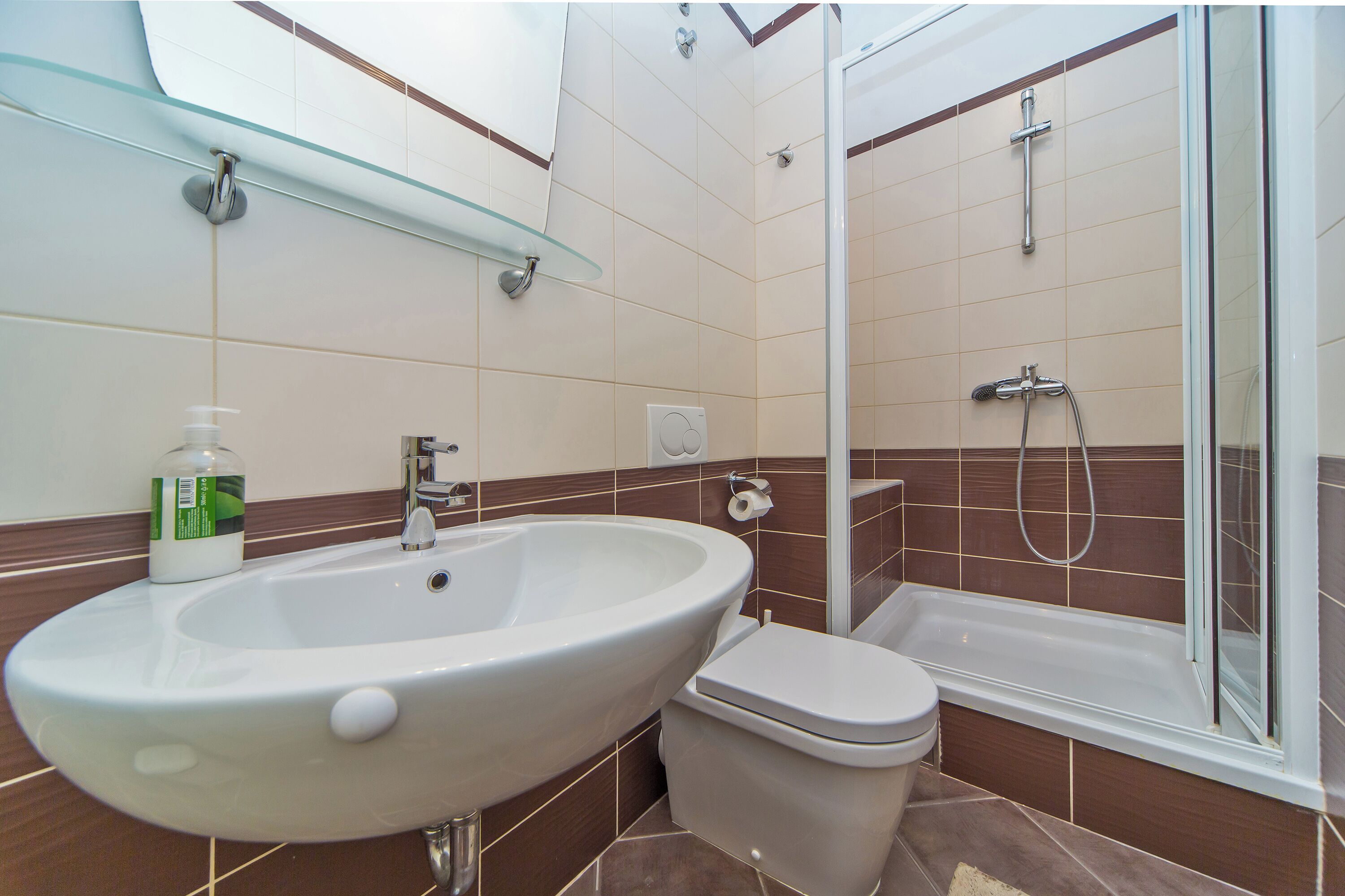 Un baño con lavamanos, inodoro y ducha con cerramiento de vidrio.