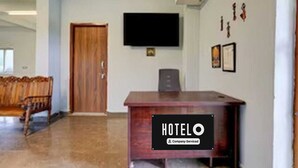 Una hall d'albergo con una reception in legno, un televisore a schermo piatto montato a parete e un'apertura che conduce in un'altra stanza.
