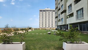 A courtyard with a grassy area, potted plants, and a building with multiple floors and balconies. - Ocean View 1-bedroom apartment with Pool View in heart of Kingston (Kingston)