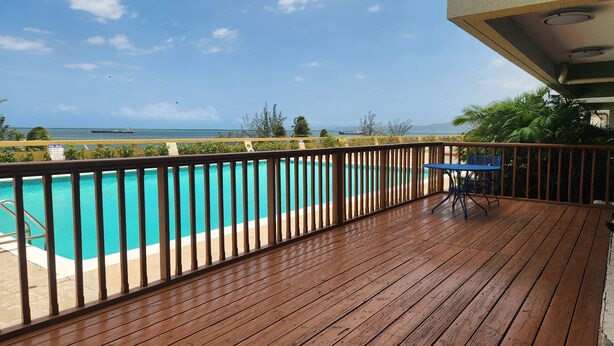 A wooden deck with a pool and a table. - Ocean View 1-bedroom apartment with Pool View in heart of Kingston (Kingston)