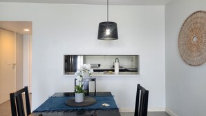 A modern dining area with a table, chairs, a hanging light fixture, a kitchen backsplash, and a decorative wall piece. - Ocean View 1-bedroom apartment with Pool View in heart of Kingston (Kingston)