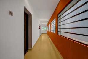 A hallway with a tiled floor, a fire extinguisher, and a door on the left. - Collection O Beach View Mahabalipuram (Tirupporur)