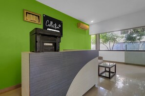 A reception desk with a sign, a framed picture, and a glass table. - Collection O Beach View Mahabalipuram (Tirupporur)