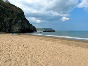 Ein sandiger Strand mit einer felsigen Klippe und einem Kajak.