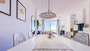 Zona pranzo moderna con un tavolo lungo, sedie dalle forme geometriche e un lampadario al centro.