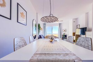 A modern dining area with a long table, geometric chairs, and a central light fixture. - 101 - Cozy Apartment with Panoramic Views in Riviera del Sol, Mijas (Calahonda)