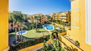 Un resort con diverse piscine, palme e edifici gialli.