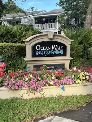 A sign for Ocean Walk with a flower bed in front.