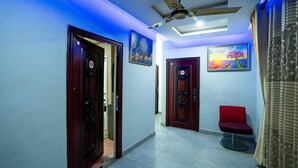 A hallway with two wooden doors, a ceiling fan, and a red chair. - Eastern Plus Hotel  (Somanya)