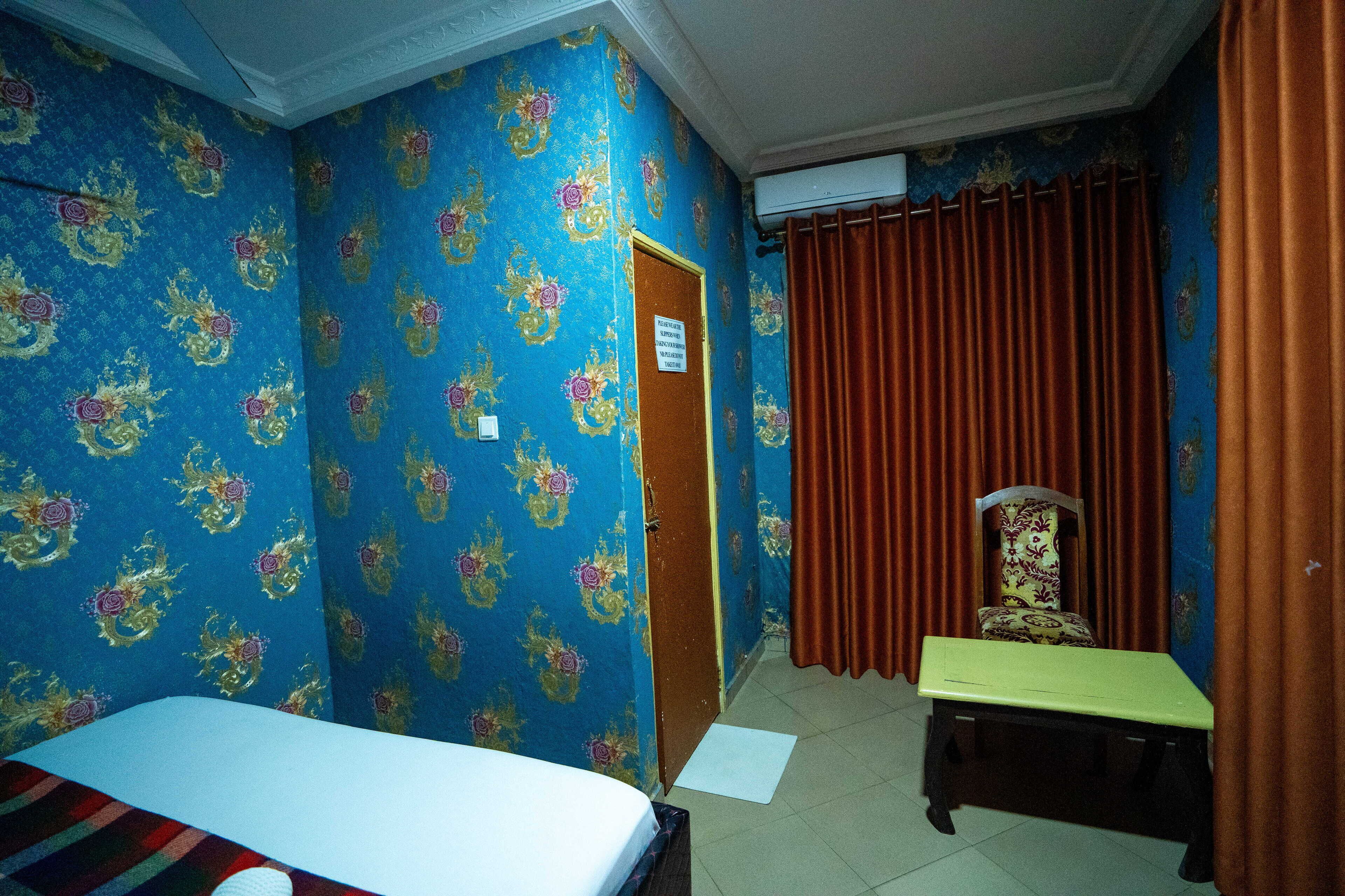 A room with a bed, a small table, a chair, and a door.