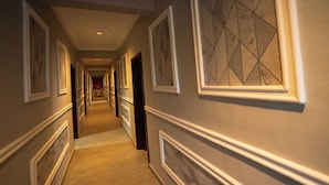 A hallway with framed artwork on the walls, a carpeted floor, and a ceiling with recessed lighting. - Eastern Plus Hotel  (Somanya)