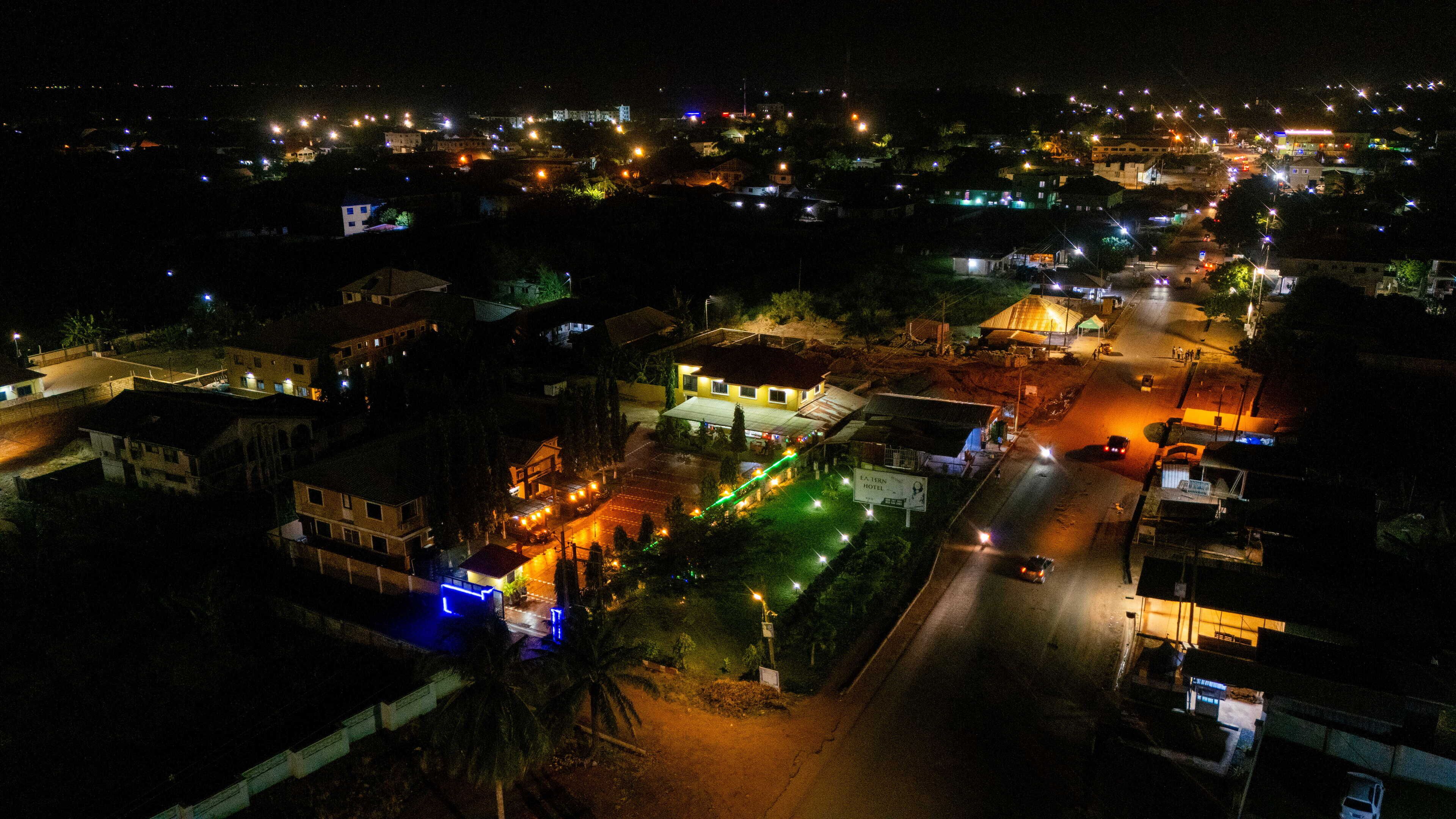An aerial view of a town at night with illuminated buildings and streets.